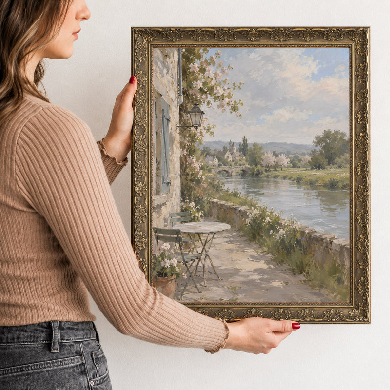 Table by the River Wall Art in a Gold Ornate Frame, held to show its size